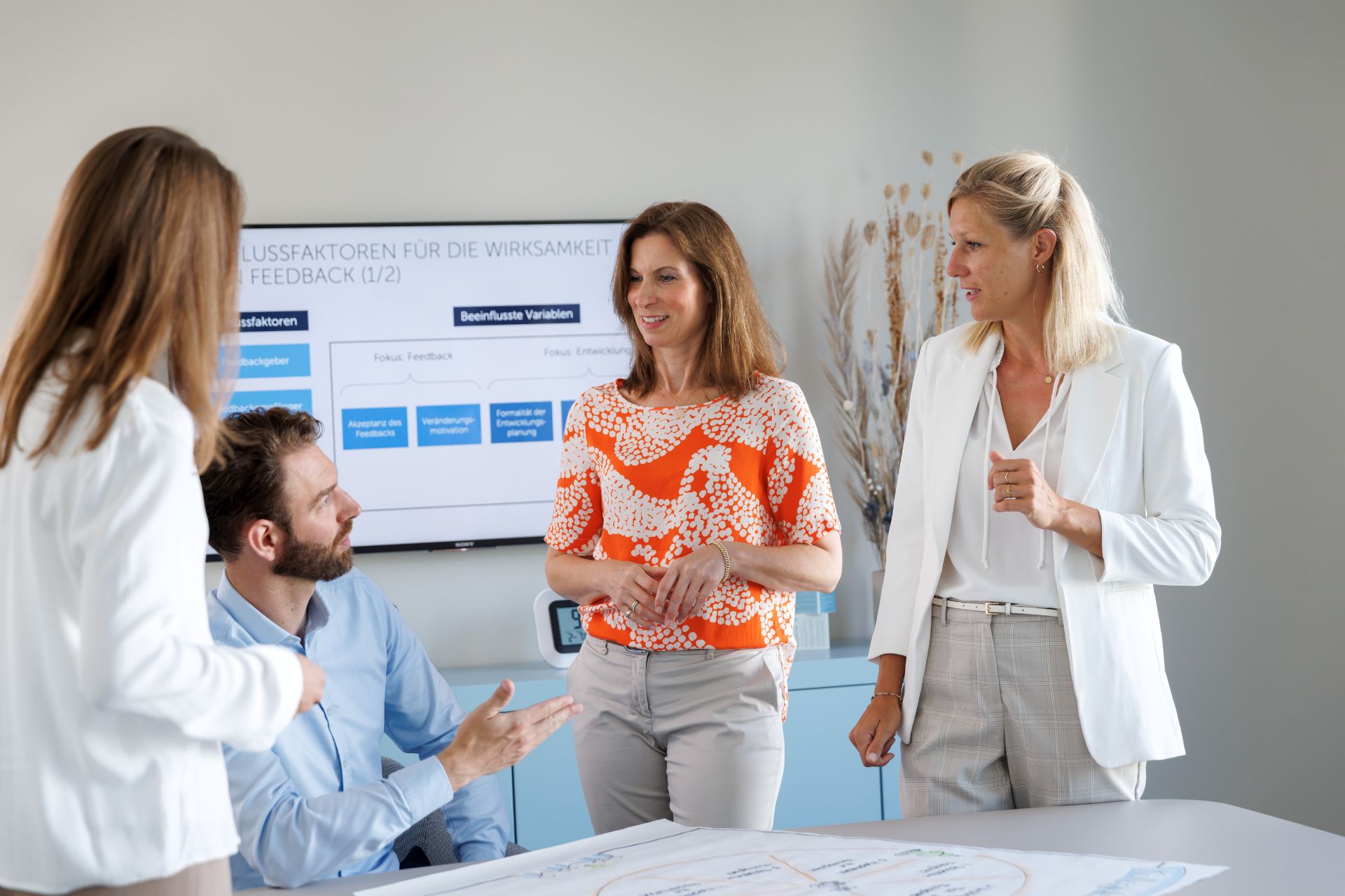 Personen im moderierten Gruppencoaching diskutieren gemeinsam vor einem Diagramm und einer Präsentation