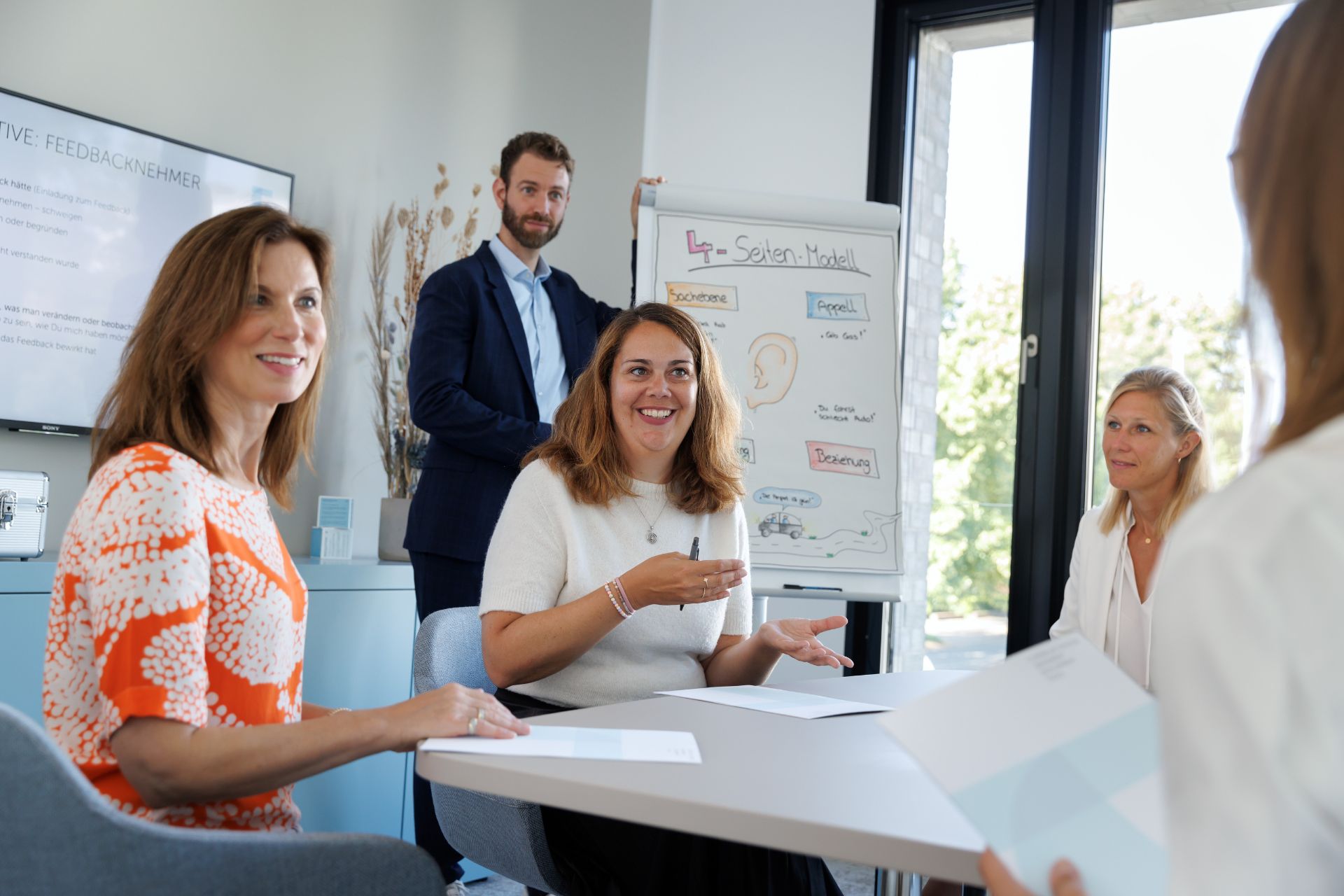 Personen in einem Kommunikationstraining im Dialog mit Flipchart mit dem Vier-Seiten-Modell