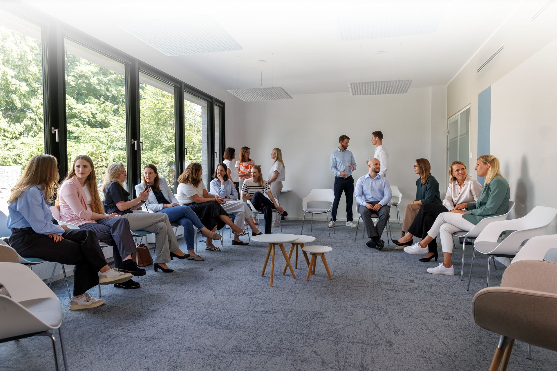 Das Team von CORNELIA TANZER sitzt in einem modernen Konferenzraum und spricht miteinander, steht für Zusammenarbeit und Austausch