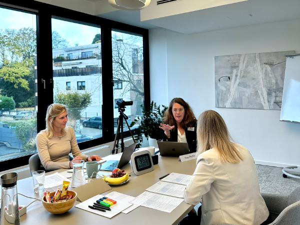 Development Center zur Führungskräfteentwicklung: Teilnehmende und Moderatorin sitzen gemeinsam am Tisch