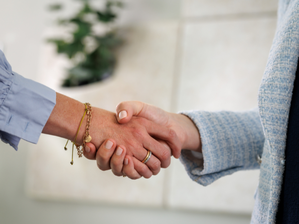 Zwei Frauen geben sich im Büro die Hand