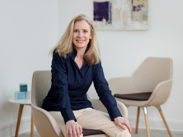 Dr. Cornelia Tanzer sitzt lächeln im modernen Büro der Cornelia Tanzer GmbH
