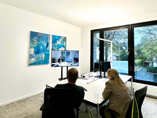 Development Center mit digitaler Übung: Teilnehmende sitzen an einem Tisch und beobachten eine Videosequenz zur Analyse und Reflexion von Kompetenzen.